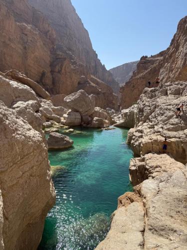 a river in the middle of a canyon at Wadi hawer tour guiding and local farm tour in Biḑ‘ah
