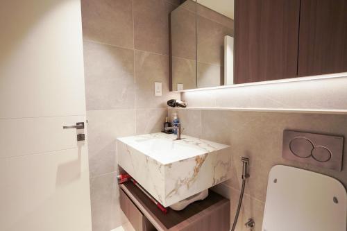 a bathroom with a marble sink and a mirror at Stylish modern studio near Miracle Garden with Gym, Pool and Padel court in Dubai