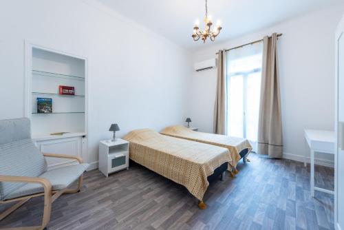 a bedroom with a bed and a chair and a window at Happyfew maison Michelet in Nice