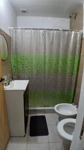 a bathroom with a green shower curtain and a toilet at La Casita de Junín in Junín