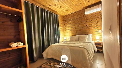 a bedroom with a bed and a wooden wall at Casa Completa | 2 Suítes + Jardim com Fogo de Chão in Urubici