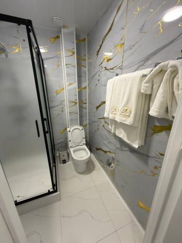 a bathroom with a shower and a toilet and towels at The Avenue Hotel in Kogon