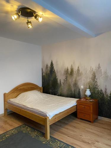 a bedroom with a bed with a forest mural on the wall at Pokoje gościnne u Faronow in Muszyna