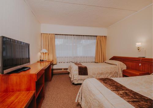 a hotel room with two beds and a flat screen tv at Villa del Rio Express in Valdivia