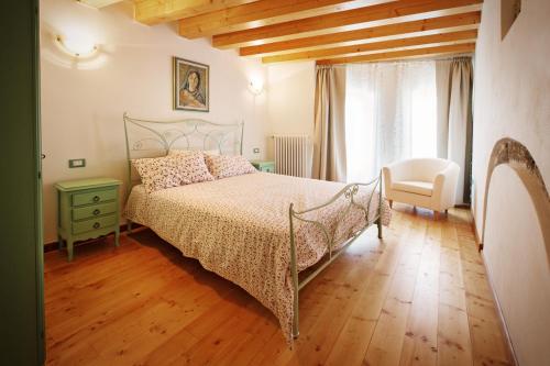 a bedroom with a bed and a chair and a window at Albergo Diffuso Tolmezzo in Tolmezzo