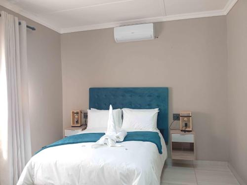 a bedroom with a large bed with a blue headboard at Joyful Home Bela-Bela in Bela-Bela
