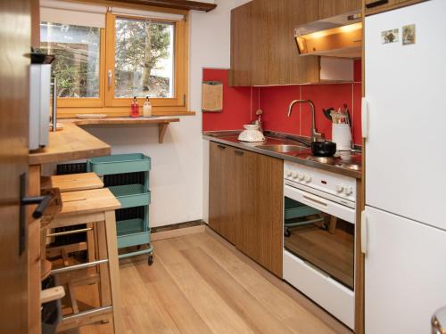 a small kitchen with red walls and wooden cabinets at Apartment Entremont 60 by Interhome in Verbier