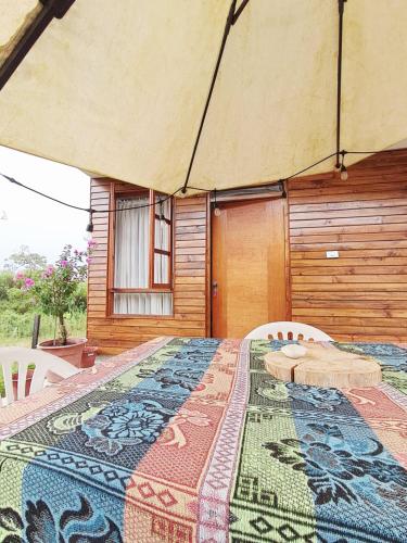 a table with a quilt on it in front of a house at Cabaña BellaVista in Oxapampa