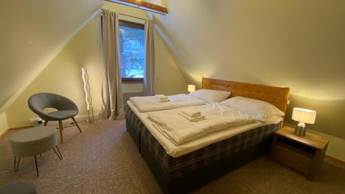 a bedroom with a bed and a chair and a window at Chalet Green Park in Stará Lesná
