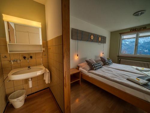 a small bedroom with a bed and a sink at Family & Mountain Lodge C'est la Vie in Hasliberg