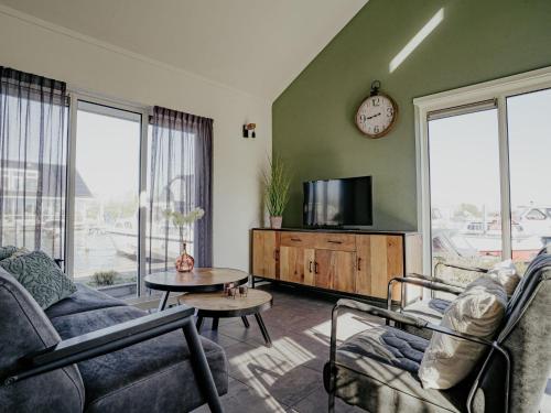 a living room with a couch and a tv at Holiday Home Kraaijennest by Interhome in Uitgeest
