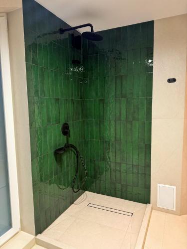 a green tiled shower with a shower head at Yaremche Soul House in Yaremche