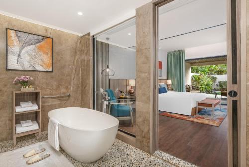 a bathroom with a tub and a bedroom at Taj Alibaug Resort & Spa, Maharashtra in Alibaug