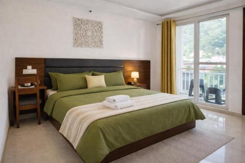 a bedroom with a green bed with two towels on it at Ima Ganga Hotel - Aesthetic, Quite Mountain View Rooms In Upper Tapovan with netflix, free airport pickup for 7 or more nights booking in Rishīkesh