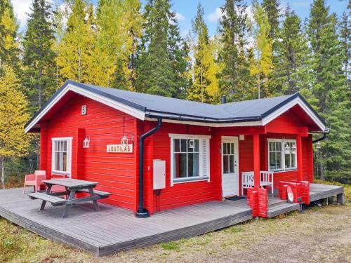 a red cabin with a picnic table on a deck at Holiday Home Joutilas by Interhome in Ruka