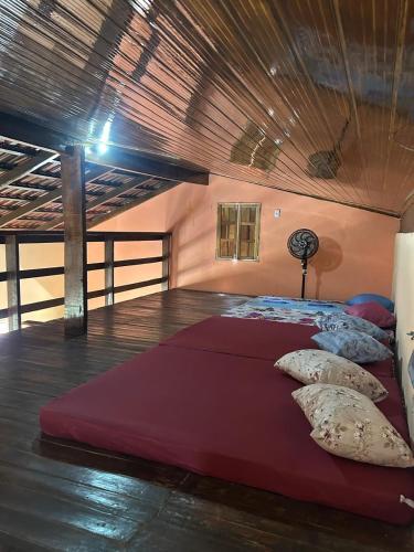 a bedroom with a large red bed with pillows at casa passos e reis in Corumbau
