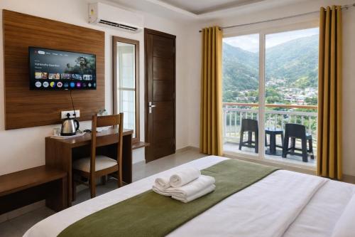 a hotel room with a bed and a desk and a window at Ima Ganga Hotel - Aesthetic, Quite Mountain View Rooms In Upper Tapovan with netflix, free airport pickup for 7 or more nights booking in Rishīkesh