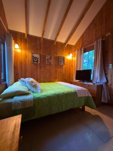 a bedroom with a bed and a desk with a computer at Cabañas en Pucón CASA TUWA in Pucón