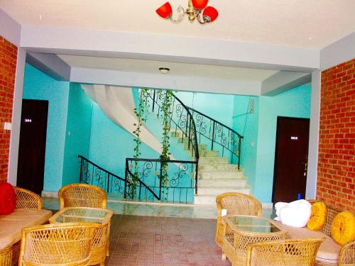 a room with wicker chairs and a staircase in the background at The North Face Inn in Pokhara