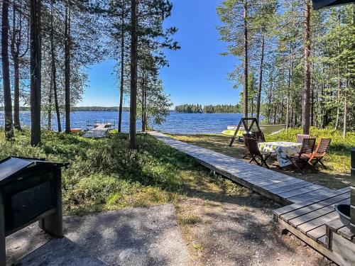 a picnic table and chairs on a boardwalk next to a lake at Holiday Home Kitkaranta by Interhome in Kitka