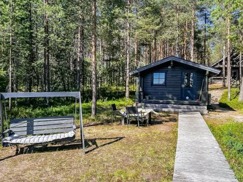 a black cabin with a bench and a table at Holiday Home Kitkaranta by Interhome in Kitka