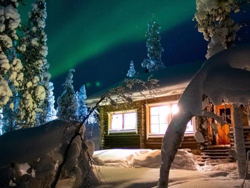 an aurora lights up the sky above a cabin at Holiday Home Villemi by Interhome in Saariselka