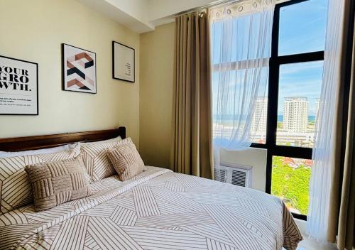 a bedroom with a bed and a large window at The Asher Mactan at Mactan Plains Residences in Mactan