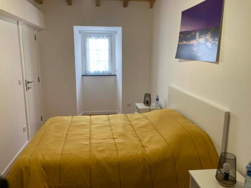 a yellow bed in a room with a window at Casa Isqueiro in Cela