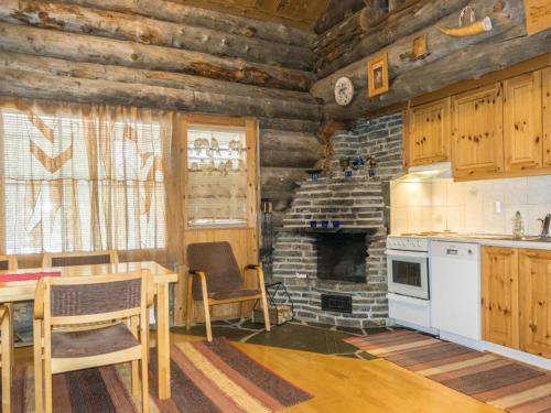 a kitchen with a table and a fireplace in a log cabin at Holiday Home Atokka by Interhome in Levi