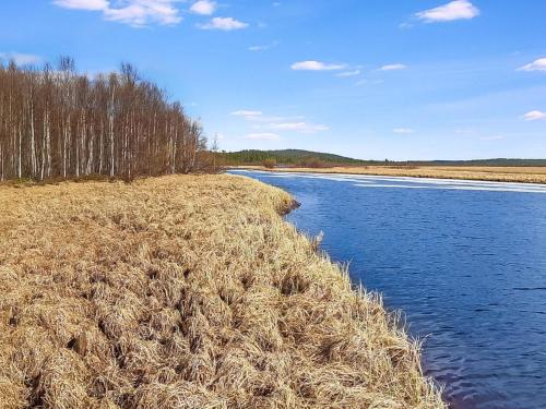 a field of hay next to a river with trees at Holiday Home Hoviranta by Interhome in Veskoniemi