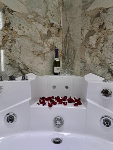 a white sink with a bottle of wine and red petals at Aqua Apartments 1 in Jagodina