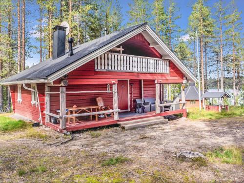 a red cabin with a porch in the woods at Holiday Home Piilola by Interhome in Raanujärvi