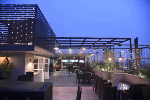 a rooftop patio with tables and chairs and lights at Hotel Picasso Prive Naraina Delhi - Couple Friendly Local IDs Accepted in New Delhi