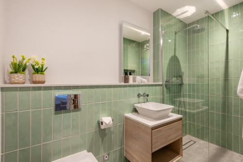 a green tiled bathroom with a sink and a mirror at Thurlestone Retreats in Thurlestone