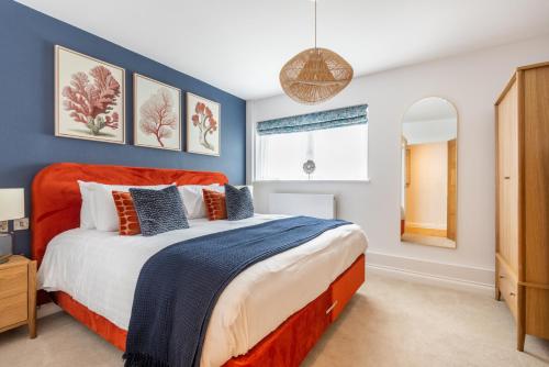 a bedroom with a bed with an orange headboard at Thurlestone Retreats in Thurlestone