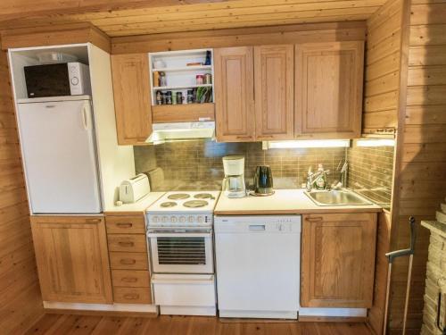 a kitchen with white appliances and wooden cabinets at Holiday Home Ylläsrova b5 - kasku by Interhome in Ylläsjärvi