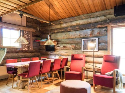 a dining room with red chairs and a wooden wall at Holiday Home Ylläspollu a by Interhome in Ylläsjärvi