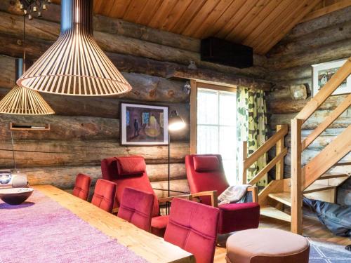 a dining room with red chairs and a wooden wall at Holiday Home Ylläspollu a by Interhome in Ylläsjärvi