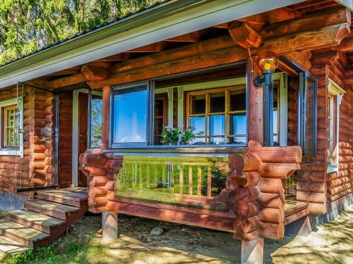 a wooden house with a porch and a window at Holiday Home Huvilakoti 2 by Interhome in Puromäki