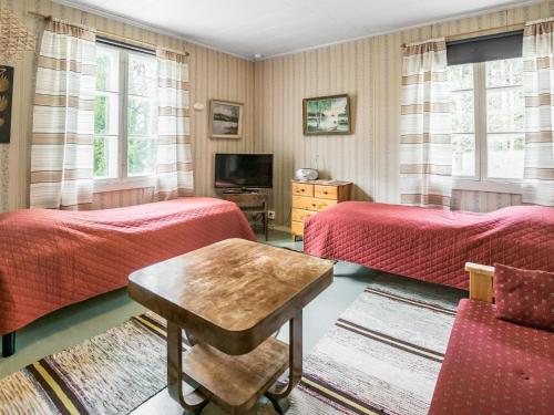 a bedroom with two beds and a table and a tv at Holiday Home Mäkitupa by Interhome in Laiterla