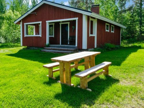 a picnic table in front of a small red house at Holiday Home 21 by Interhome in Varparanta