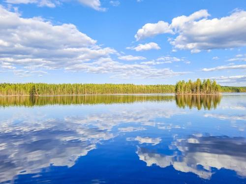 a large lake with trees and clouds in the sky at Holiday Home Pilkkaniemi by Interhome in Rontsa
