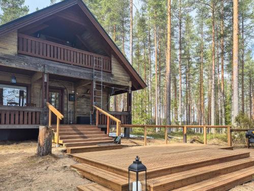 a log cabin with a wooden deck in the woods at Holiday Home Pilkkaniemi by Interhome in Rontsa