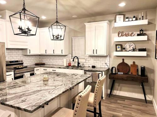 a kitchen with white cabinets and a marble counter top at Mins to Granbury Med Ctr, Mins to Lake, Firepit, Stunning Modern Kitchen in Granbury