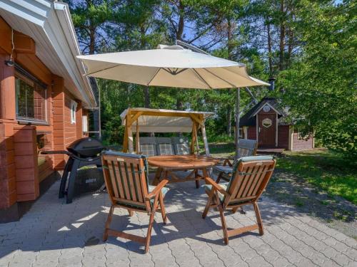 a table and chairs with an umbrella and a grill at Holiday Home Kannelpirtti 1 by Interhome in Puromäki