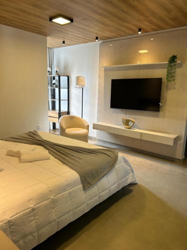 a bedroom with a large bed and a flat screen tv at Condômino Max life in Pipa