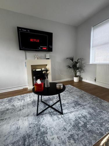 a living room with a table and a tv on the wall at Oakleigh Way, Carlisle - 2 Bedroom, sleeps 4, Fully furnished in Carlisle