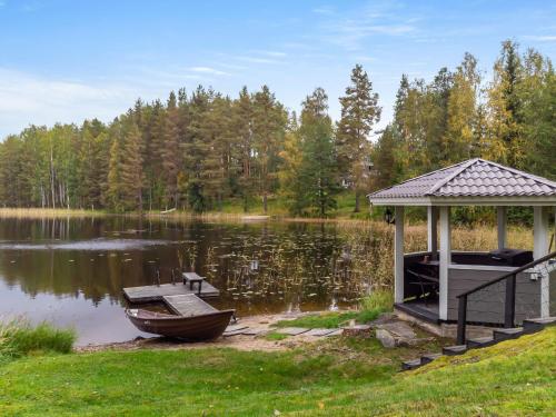 a gazebo and a boat on a lake at Holiday Home Kiikkukallio by Interhome in Hankamäki