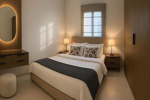 a bedroom with a bed with two lamps and a mirror at Sunshine Flat in Al Khobar