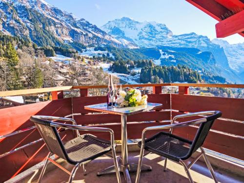 a table and chairs on a balcony with mountains at Apartment Eiger Residence Apt-A-425 by Interhome in Wengen